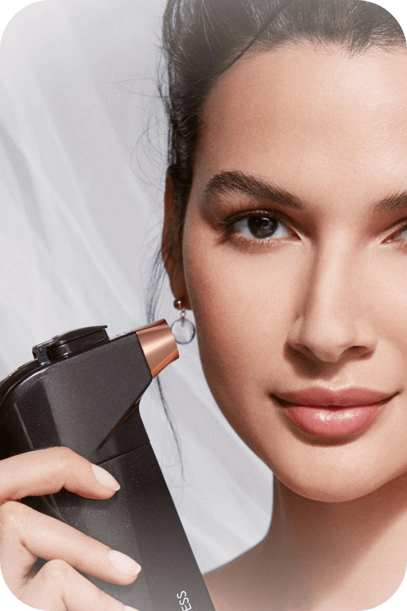 Woman holding airbrush spray device next to her cheek