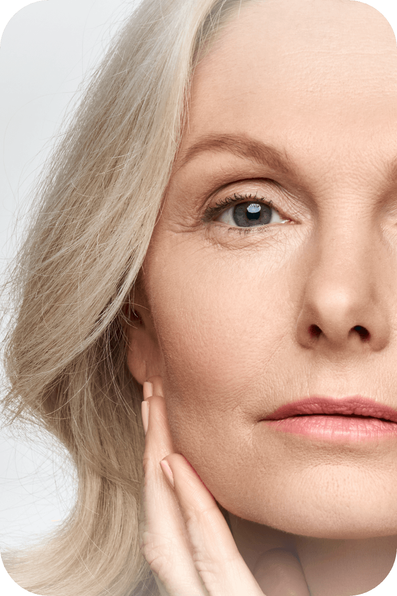 Close up photo of a middle aged woman's skin as she poses with her hand gently touching her face