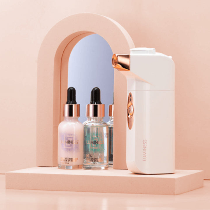 Lifestyle photo of two skincare serums next to a white skincare airbrush device.