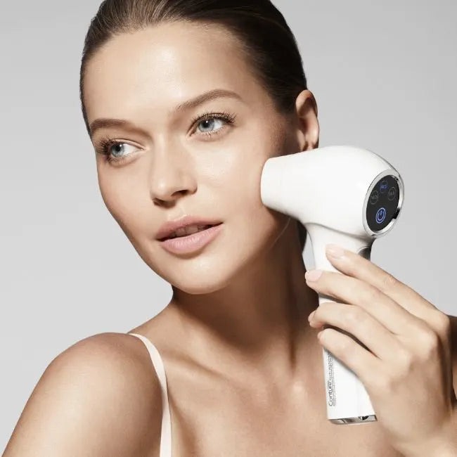 Close up of woman holding a skincare toning device to her left cheek